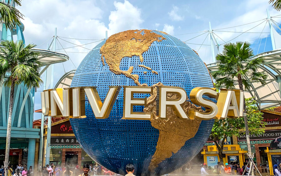 Universal Studios globe surrounded by palm trees and vibrant park atmosphere.