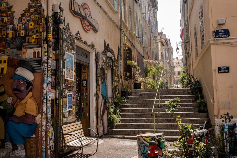 Vibrant alleyway featuring colorful murals, greenery, and European architecture in urban setting.