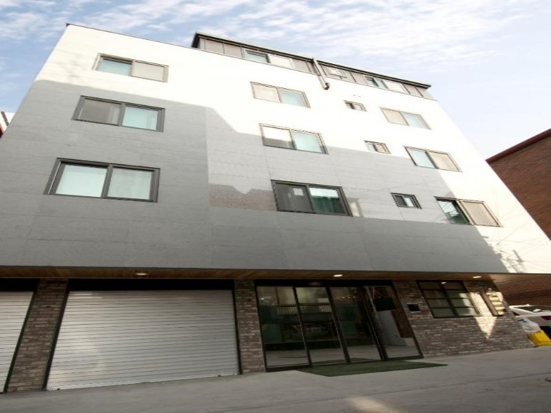 Twin Rabbit Guesthouse modern urban apartment building facade with ground-level garages and glass entrance.