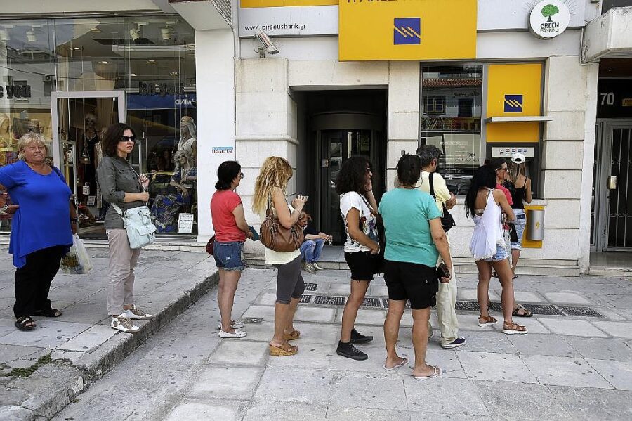People waiting at sunny urban ATM outside vibrant bank, checking phones and chatting.