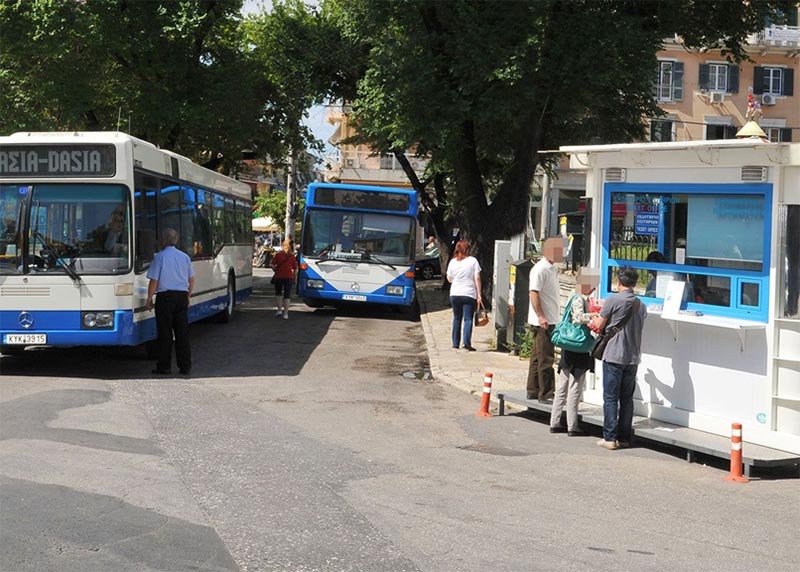 Bustling urban bus terminal scene with commuters, buses, and ticket booth in a lively neighborhood.