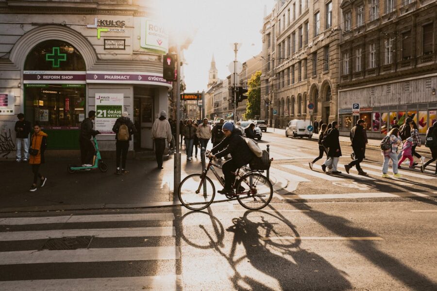 Cyclist and pedestrians in Budapest during golden hour with historic and modern architecture.