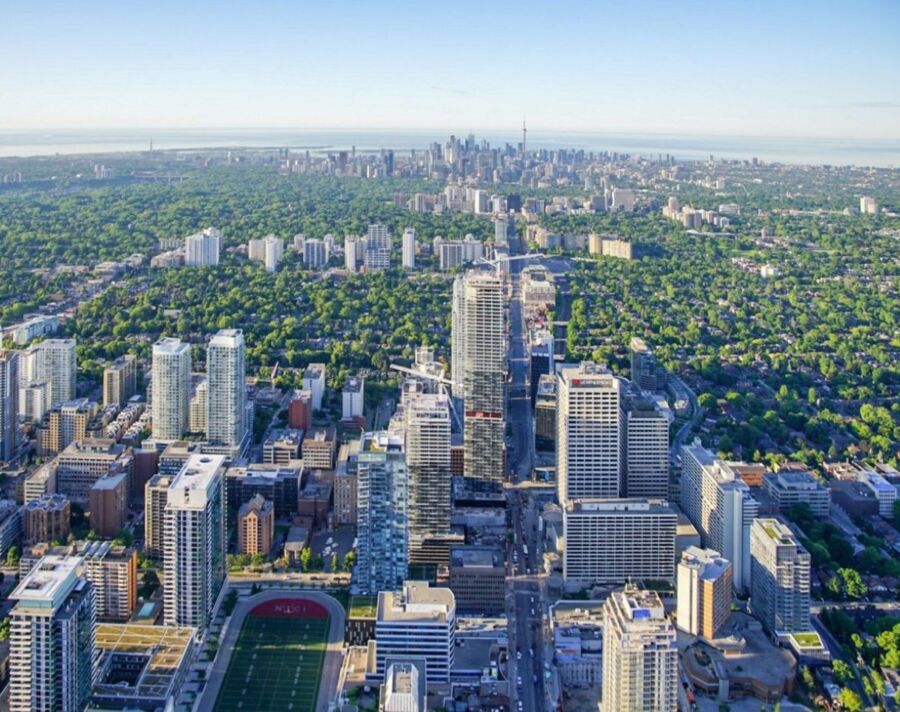 Aerial view of Toronto’s urban landscape with skyscrapers and lush greenery.