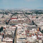 Aerial view of vibrant city landscape with diverse architecture and scenic natural backdrop.