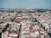 Aerial view of vibrant city landscape with diverse architecture and scenic natural backdrop.