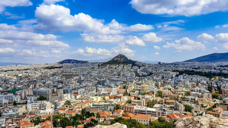 Panoramic view of Athens cityscape, featuring rooftops, Mount Lycabettus, and diverse architecture.
