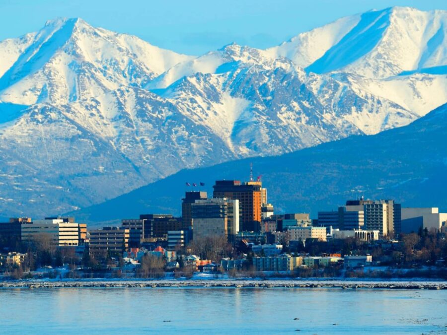 Cityscape with mountains, water reflection; Anchorage, Alaska’s blend of urban and natural beauty.