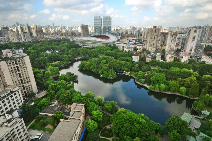Aerial view of Hongkou  urban skyline with vibrant greenery, serene lake, and modern stadium.