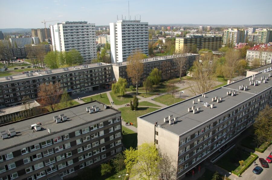 Modern urban landscape with apartment buildings, green communal spaces, and diverse architectural styles.