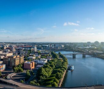 Aerial view of modern cityscape, vibrant architecture, lush greenery, and serene river.