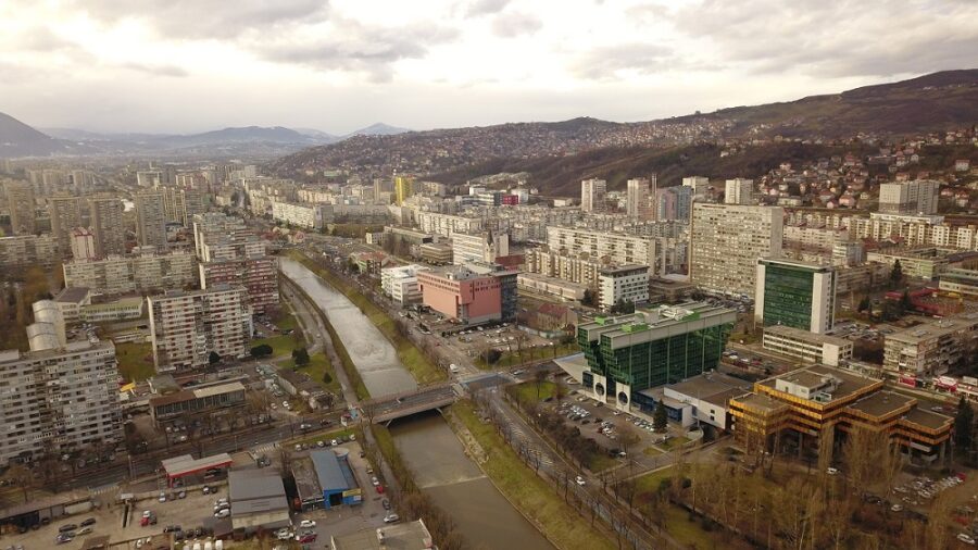 Aerial cityscape of river valley urban skyline with bridges, apartments, hills and modern office buildings.