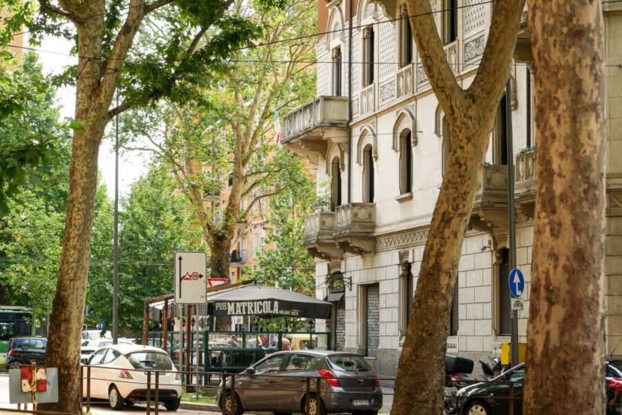 Charming Italian street scene with trees, classic architecture, and outdoor pub.