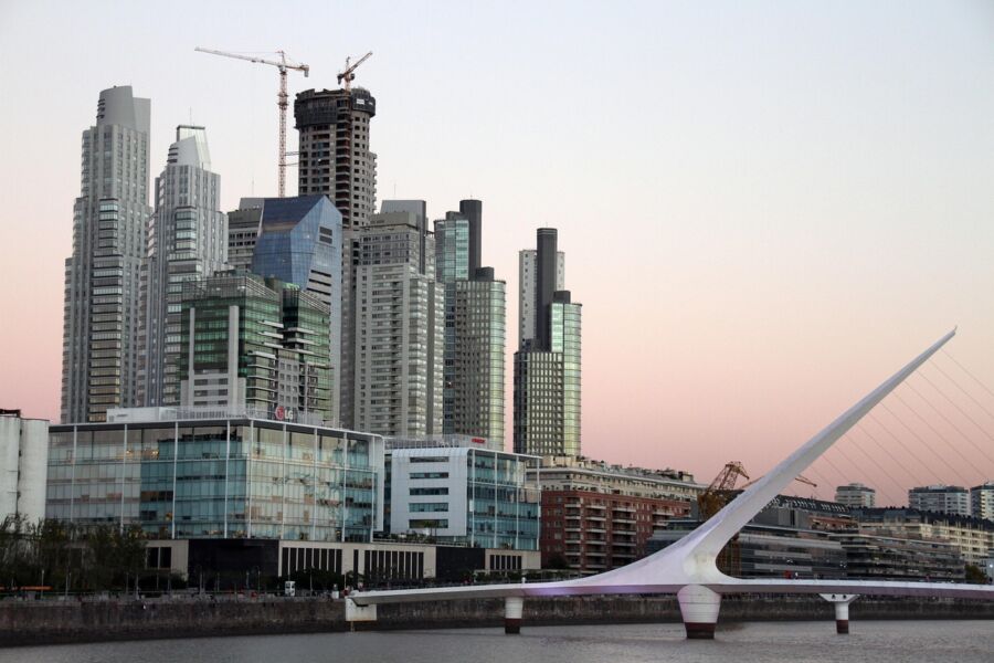 Modern Puerto Madero skyline at dusk with skyscrapers, bridge, and serene water reflection.