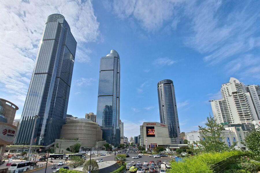 Vibrant Xuhui cityscape with glass skyscrapers, green spaces, and bustling streets on a sunny day.