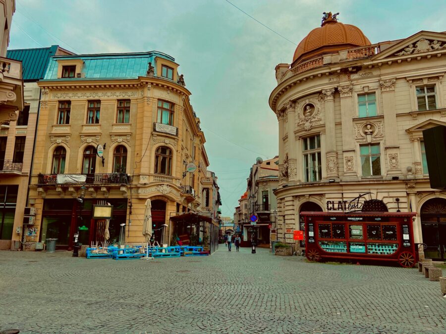 Historic urban street scene in Bucharest with ornate architecture, cobblestone streets, and café culture.