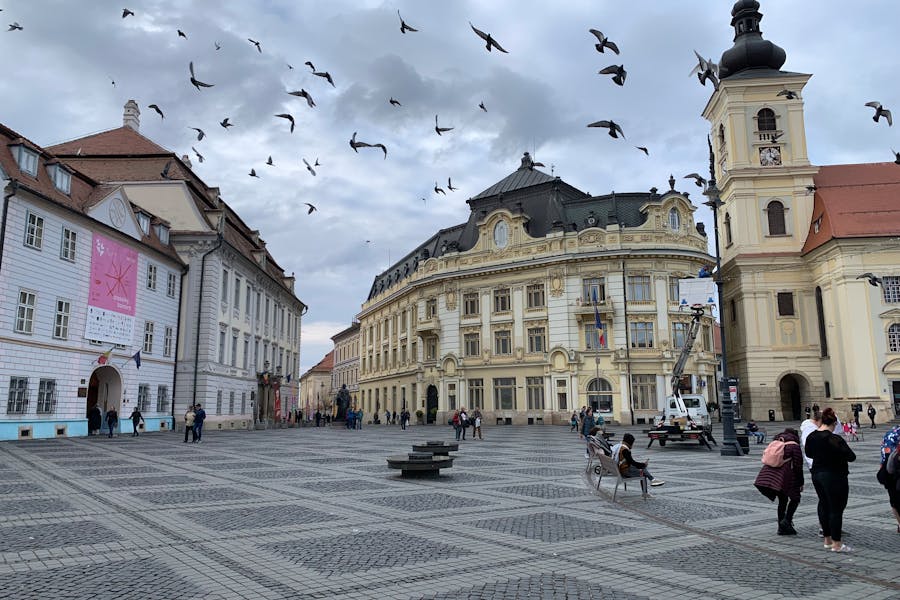 Historic urban plaza in Sibiu, Romania, showcasing diverse architecture and lively community activities.