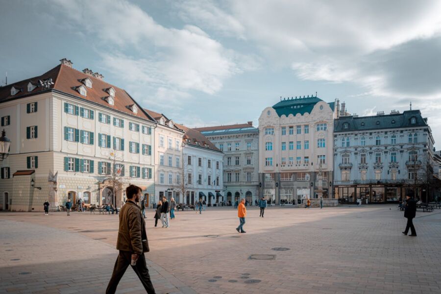 Vibrant urban square with diverse architecture, pedestrians, and lively outdoor cafés.