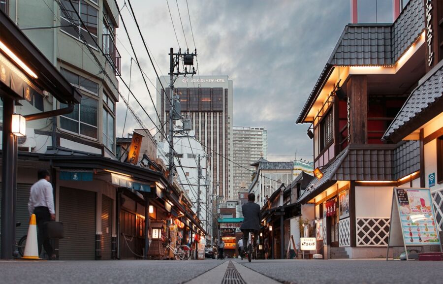 Traditional Japanese street scene with modern high-rise, blending culture and urban life.