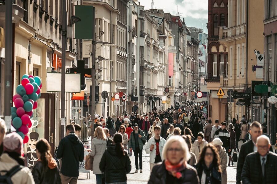 Pickpocketing at vibrant urban street scene with diverse crowd, colorful balloons, historic and modern architecture.