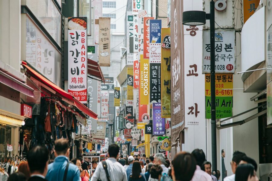 Vibrant Myeongdong street scene with colorful signs, diverse crowd, shops, and restaurants.