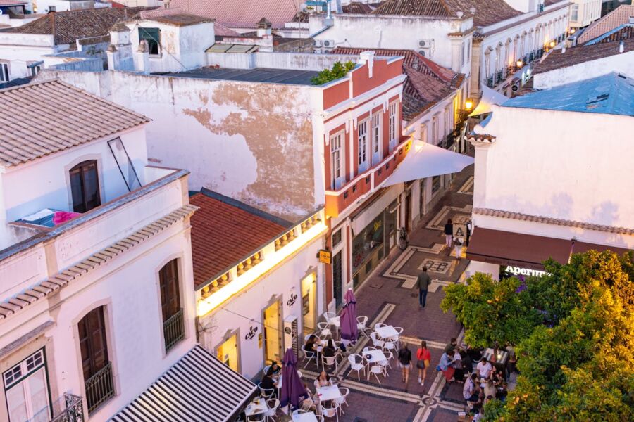 Charming Faro historic street scene with lively café, architecture, and greenery at twilight.