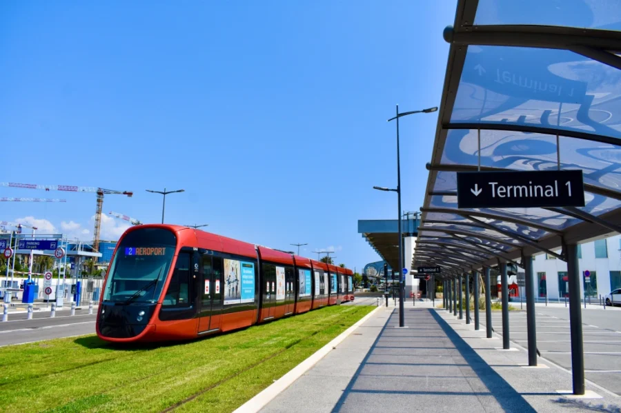 Modern red tram to airport in urban transport terminal with ongoing construction.