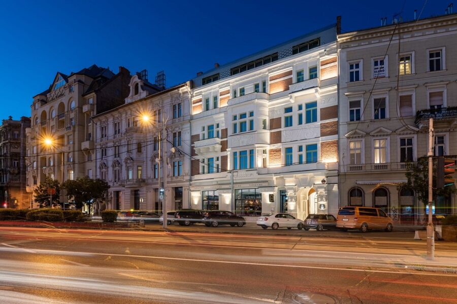 Urban evening scene featuring diverse architecture, bustling street activity, and lush greenery.