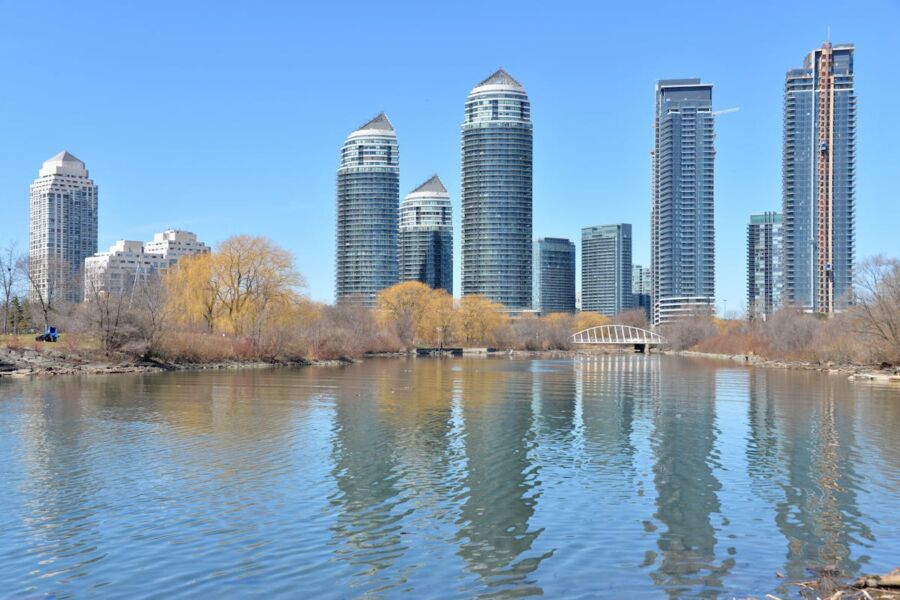 Urban skyline with skyscrapers, water, and blooming spring trees reflecting modern architectural harmony.