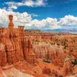 Scenic view of Bryce Canyon National Park, showcasing its iconic hoodoos and vibrant red rock formations under a clear sky.