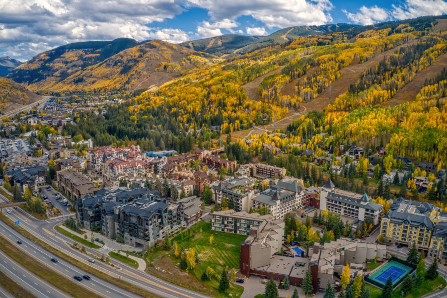 Stunning aerial shot of Vail, Colorado, highlighting colorful autumn trees and the picturesque mountain backdrop