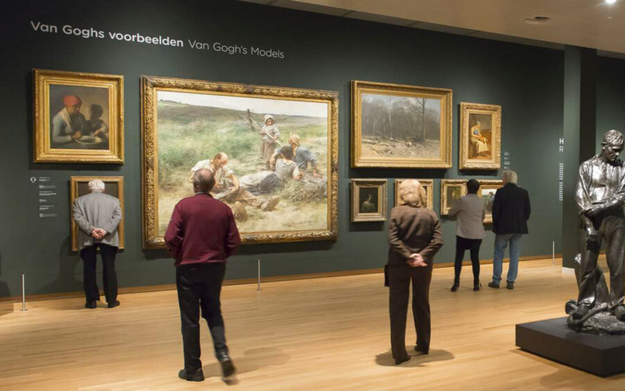 Van Gogh art exhibition with paintings, sculptures, and engaged visitors.