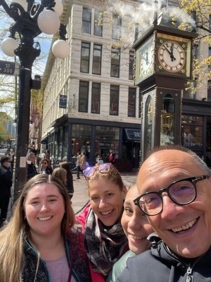 Friends posing for a selfie in front of a clock, enjoying a personalized walking tour in Vancouver.
