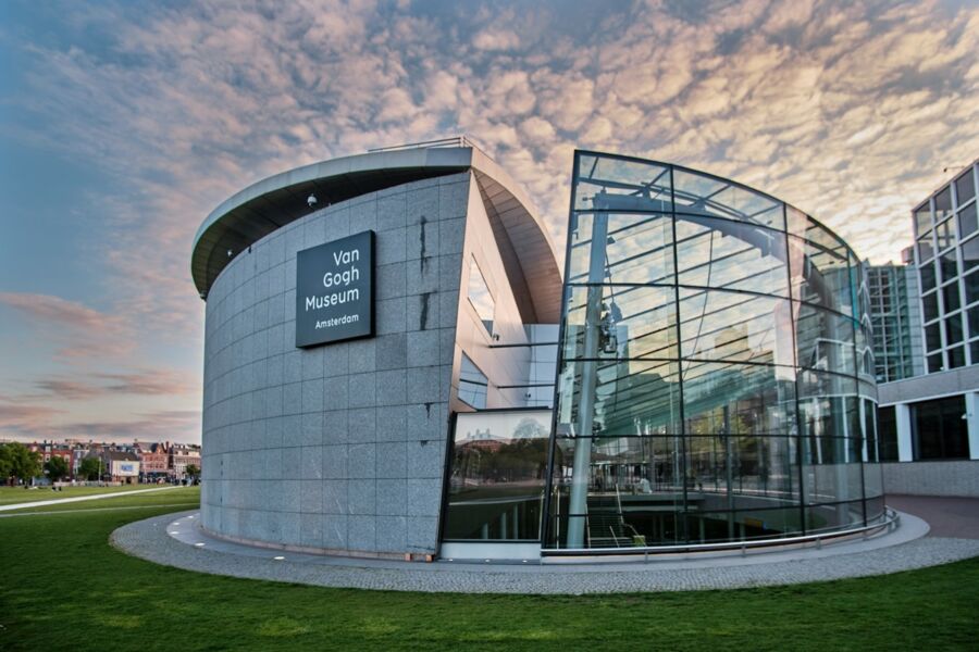 Van Gogh Museum in Amsterdam: modern architecture with curved stone facade and large glass panels.