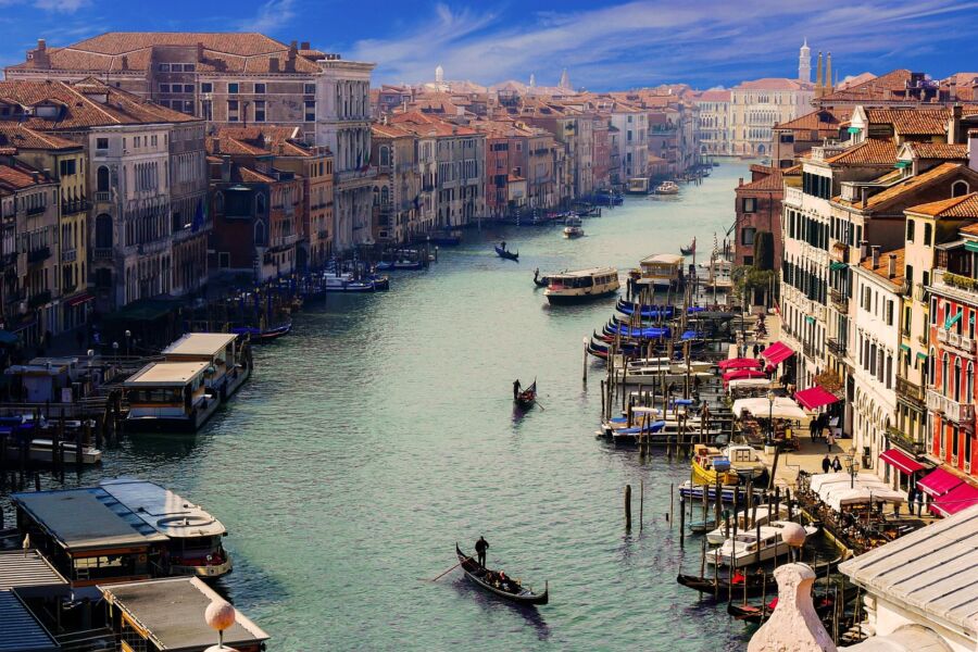 Venice canal view: gondolas, historic architecture, vibrant atmosphere, dining, bell towers.