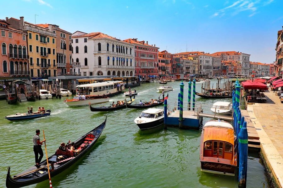 Venice canal scene with gondolas, vibrant architecture, and sunny skies.
