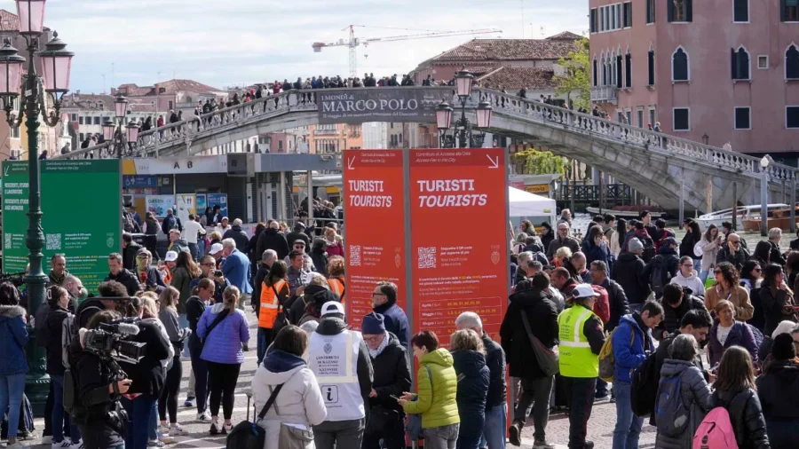 Tourists in Venice bustling around Marco Polo Bridge, vibrant signs, and Venetian architecture.