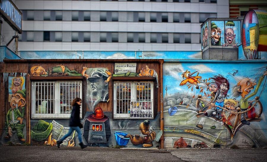 Colorful urban mural with cartoonish characters and playful animals on a city building.
