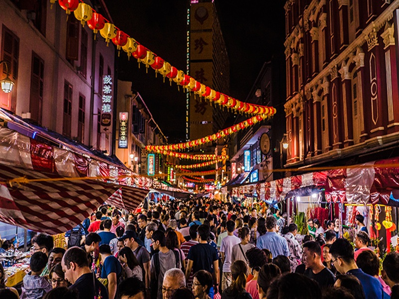 Festive night market with lanterns, crowds, food stalls, and cultural celebration.