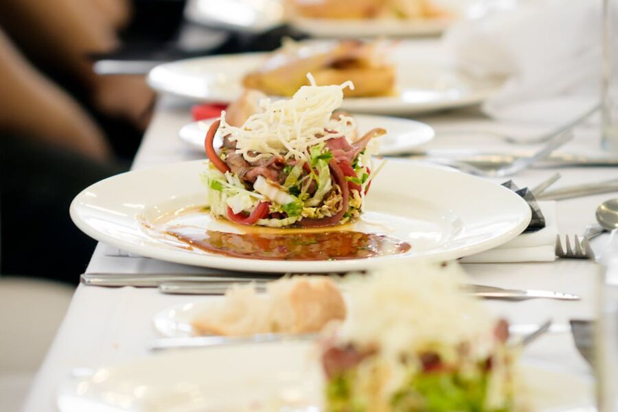 Elegant layered salad with fresh vegetables and cheese on a formal dining table.