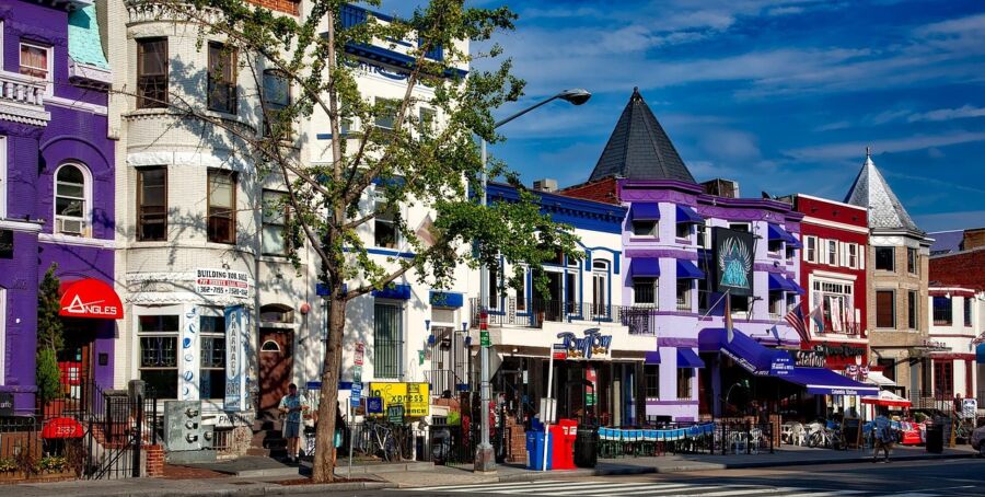 Vibrant Adams Morgan urban street scene with colorful buildings, trees, shops, and people in Washington, D.C.