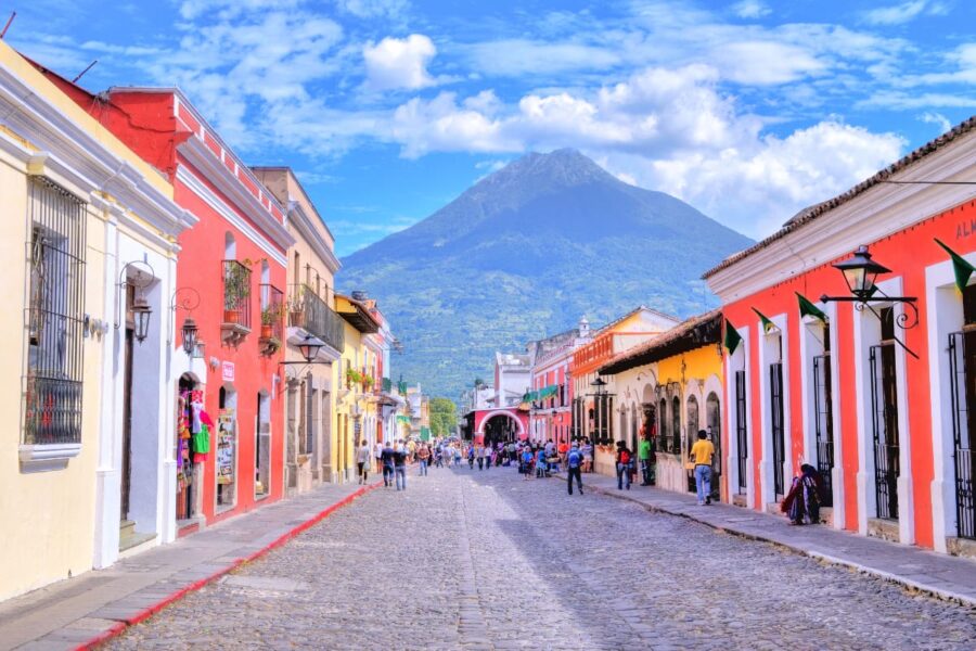 Colorful Central American street with volcanic backdrop, vibrant buildings, and lively atmosphere.