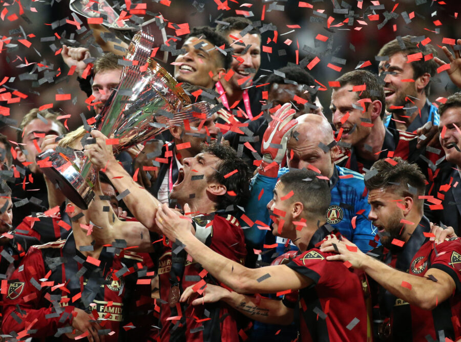 Championship celebration: soccer players celebrate victory, holding trophy, surrounded by confetti.