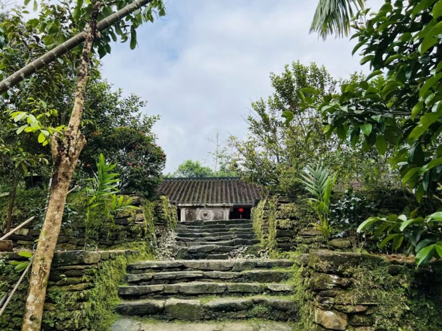 Stone steps lead to a small house surrounded by lush jungle, part of the Vietnam Loc Yen Ancient Village Tour.