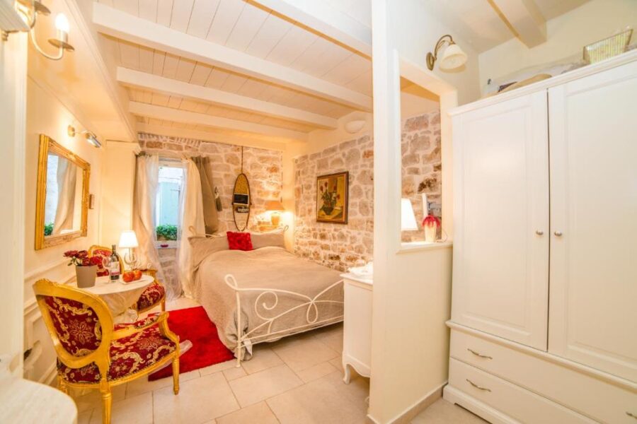 Cozy bedroom in Villa Segalla Rovinj featuring a bed, dresser, and a chair, creating a warm and inviting atmosphere.