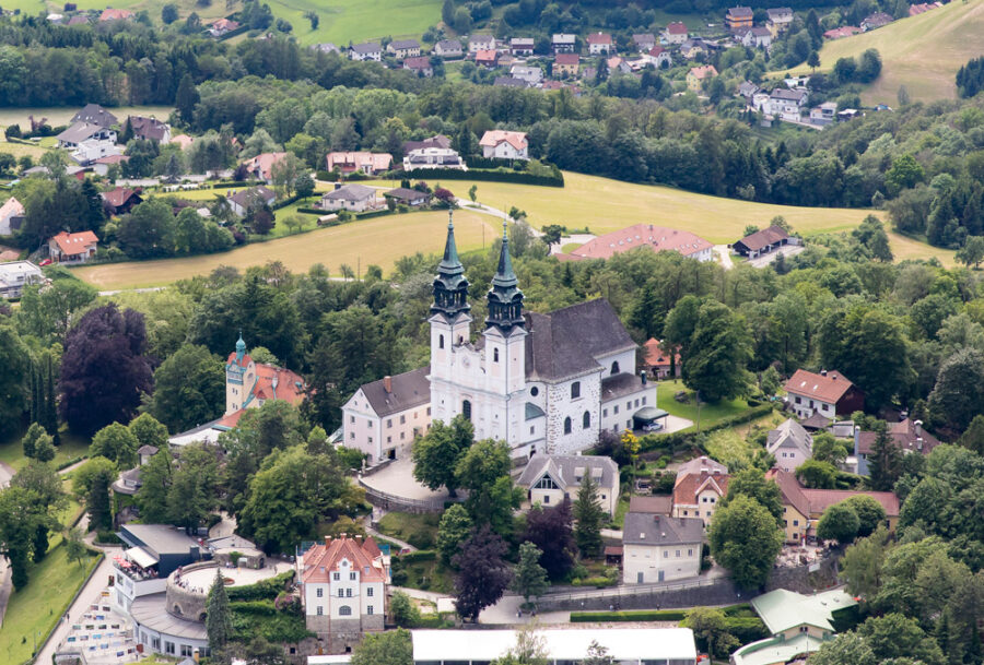Aerial view of Pöstlingberg church and historic village amid rolling Austrian countryside.