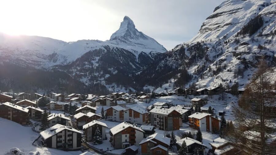 The Matterhorn towers majestically over the village of Zermatt, surrounded by picturesque alpine scenery.
