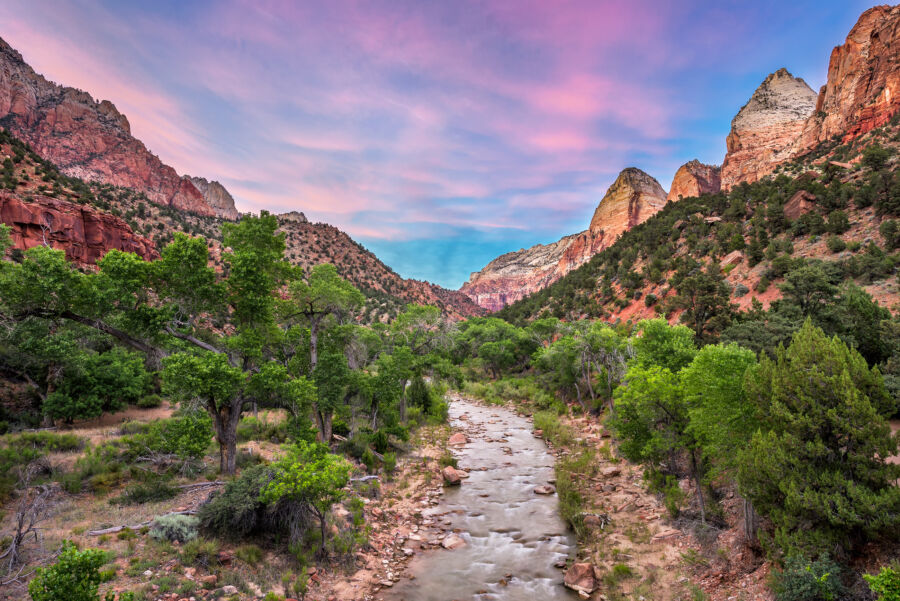 The Virgin River flows through Zion National Park, illuminated by a stunning sunset that paints the sky in vibrant colors