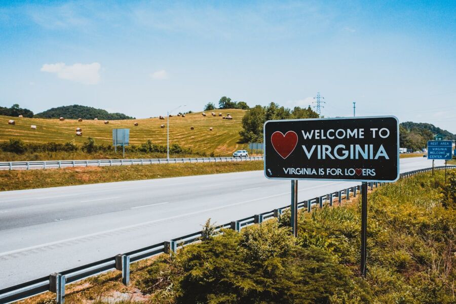 Entrance to Virginia: Welcome to Virginia sign, scenic highway, rolling hills, clear skies.