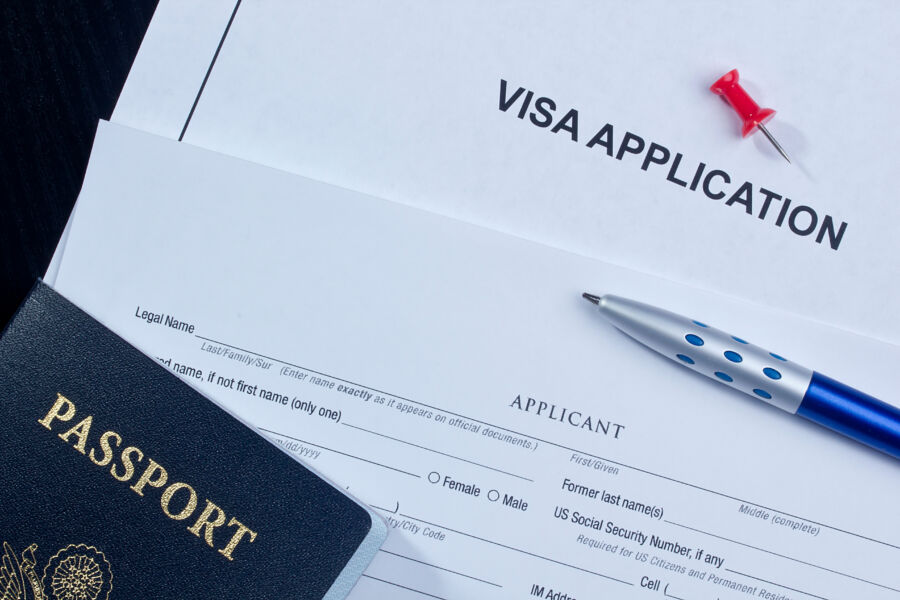 Close-up of a visa application next to a passport and travel documents on a flat surface