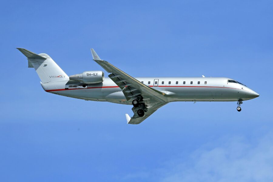 A sleek Bombardier Challenger 300 jet gleaming against a clear blue sky.